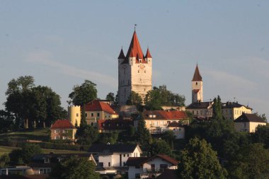 HAAG OBERBAYERN, GERMANY - 31 Mayıs 2025: Schlossturm Kulesi 'nin yükseltilmiş sabah manzarası ve Oberbayern' deki Haag 'daki yeşil ağaçlar ve geleneksel köy evleri tarafından çerçevelenmiş kilise. Yüksek kalite fotoğraf