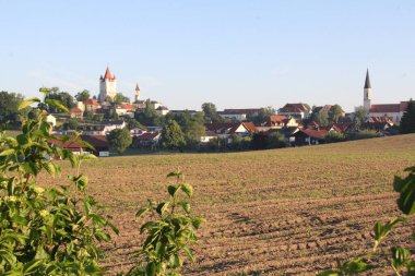 Köy çatılarının üstündeki kilise kuleleri. Önünde yeşil çalılar olan tarlalar boyunca görülmüşler. Yüksek kalite fotoğraf
