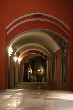 WASSERBURG, ALMANY - 13 Mayıs 2025: geceleyin Wasserburg 'da tarihi bir binada kırmızı ve bej duvarlar ve tavan ışıkları ile aydınlatılmış kemerli koridor. Yüksek kalite fotoğraf