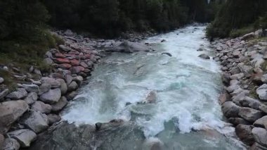 Avusturya 'daki Krimmml Şelaleleri yakınlarındaki kayalık vadiden akan turkuaz akıntılı dağ nehri yazın sık ormanlarla çevrilidir. Yüksek kaliteli FullHD görüntüler