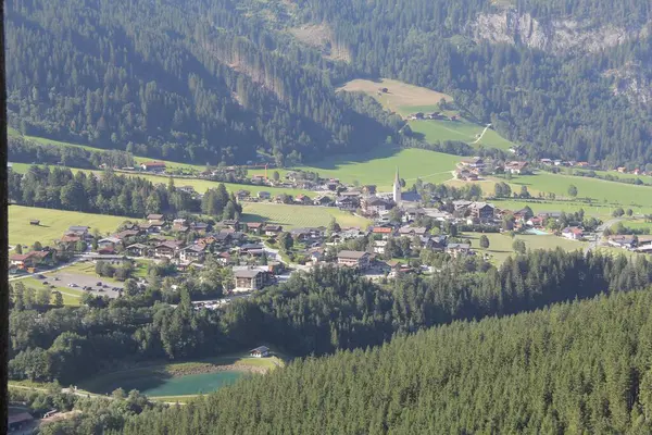 KRIMML, AUSTRIA - 8 Ağustos 2025: Yeşil tarlalar ve orman dağlarıyla çevrili Krimmml köyünün panoramik manzarası. Yüksek kalite fotoğraf