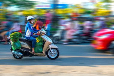 Ho Chi Minh City, Vietnam - 31 Ocak 2022: Vietnamlılar, Vietnam 'ın Ho Chi Minh şehrinde yeni yıl için dekorasyon amaçlı bir evin arkasında elinde çiçek veya kumkuat kabıyla motosiklet kullanıyorlar