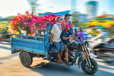 Ho Chi Minh City, Vietnam - 31 Ocak 2022: Vietnamlılar, Vietnam 'ın Ho Chi Minh şehrinde yeni yıl için dekorasyon amaçlı bir evin arkasında elinde çiçek veya kumkuat kabıyla motosiklet kullanıyorlar