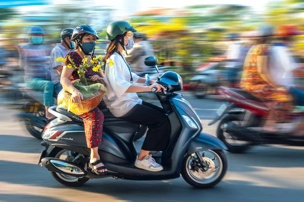 stock image Ho Chi Minh City, Vietnam - January 31st, 2022: People Vietnamese driving a motorbike with holder flower or kumquat pot behind decoration purposes house for Lunar new year in Ho Chi Minh, Vietnam