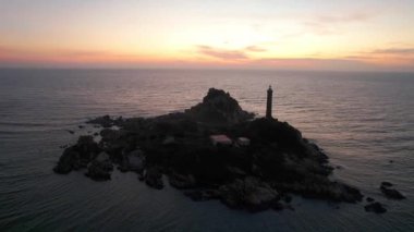 Güneşin doğuşunda antik deniz feneriyle küçük bir adanın manzarası güzel ve huzurludur. Bu sadece Vietnam 'daki bir adada bulunan eski bir deniz feneri.