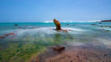 Time lapse rocky beach and green moss in night and sunrise sky at a beautiful beach in central Vietnam