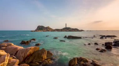 Time lapse landscape of the small island with the ancient lighthouse at sunset sky is beautiful and peaceful. This is the only ancient lighthouse is located on the island in Vietnam