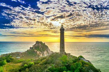 Güneşin doğuşunda antik deniz feneriyle küçük bir adanın manzarası güzel ve huzurludur. Bu sadece Vietnam 'daki bir adada bulunan eski bir deniz feneri.