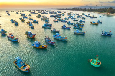Güneş batımında Mui Ne 'nin hava manzaralı balıkçı köyü. Fırtınalardan korunmak için yüzlerce tekne demirli. Burası Vietnam' ın merkezinde güzel bir koy.