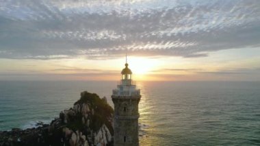 Güneşin doğuşunda antik deniz feneriyle küçük bir adanın havadan görünüşü güzel ve huzur vericidir. Bu sadece Vietnam 'daki bir adada bulunan eski bir deniz feneri.