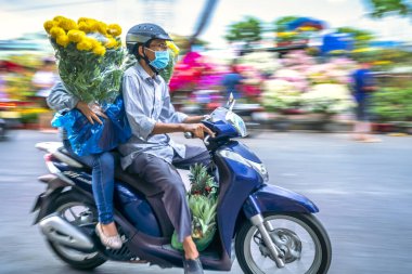 Ho Chi Minh City, Vietnam - 20 Ocak 2023: Vietnamlılar, Vietnam 'ın Ho Chi Minh şehrinde yeni yıl için dekorasyon amaçlı evin arkasında çiçek saksısı olan motosiklet kullanıyorlar