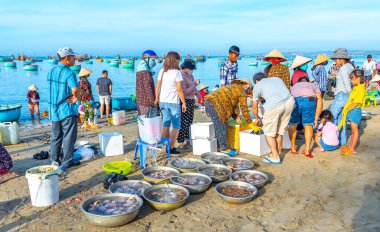 Phan Thiet, Vietnam - 12 Şubat 2023: Balık pazarı deniz manzarası insanlar sepette balık satışı için toplandı, kürek çeken balıkçılar Phan Thiet, Vietnam 'da bir balıkçı köyü getirdiler