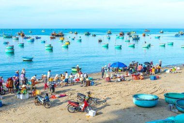 Phan Thiet, Vietnam - 12 Şubat 2023: Balık pazarı deniz manzarası insanlar sepette balık satışı için toplandı, kürek çeken balıkçılar Phan Thiet, Vietnam 'da bir balıkçı köyü getirdiler