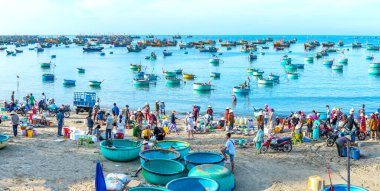 Phan Thiet, Vietnam - 12 Şubat 2023: Balık pazarı deniz manzarası insanlar sepette balık satışı için toplandı, kürek çeken balıkçılar Phan Thiet, Vietnam 'da bir balıkçı köyü getirdiler