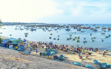 Phan Thiet, Vietnam - 12 Şubat 2023: Balık pazarı deniz manzarası insanlar sepette balık satışı için toplandı, kürek çeken balıkçılar Phan Thiet, Vietnam 'da bir balıkçı köyü getirdiler