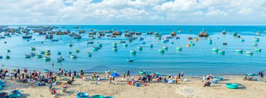 Phan Thiet, Vietnam - 12 Şubat 2023: Balık pazarı deniz manzarası insanlar sepette balık satışı için toplandı, kürek çeken balıkçılar Phan Thiet, Vietnam 'da bir balıkçı köyü getirdiler