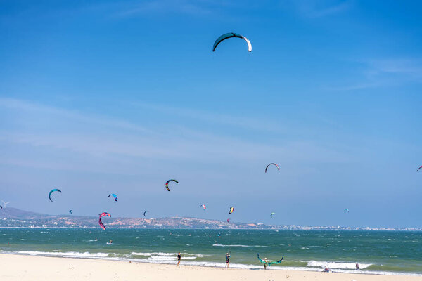 Mui Ne, Vietnam - February 11th, 2023: Kite-surfing. Many silhouettes of kites in the sky of Mui Ne bay and performs all kinds of stunts. The concept of sports, health, recreation. Holidays on nature
