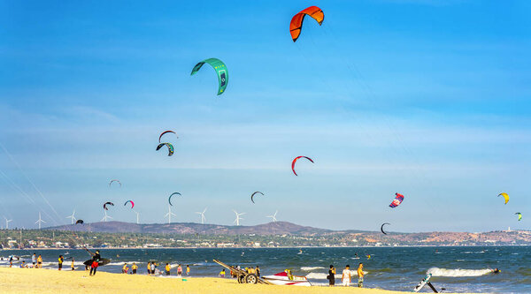 Mui Ne, Vietnam - February 11th, 2023: Kite-surfing. Many silhouettes of kites in the sky of Mui Ne bay and performs all kinds of stunts. The concept of sports, health, recreation. Holidays on nature