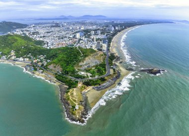 Vung Tau city aerial view with beautiful sunset and so many boats. Panoramic coastal Vung Tau view from above, with waves, coastline, streets, coconut trees and Tao Phung mountain in Vietnam.