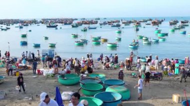 Phan Thiet, Vietnam - 12 Şubat 2023: Balık pazarı deniz manzarası insanlar sepette balık satışı için toplandı, kürek çeken balıkçılar Phan Thiet, Vietnam 'da bir balıkçı köyü getirdiler