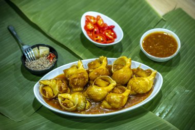 Steamed Spotted Babylon Blanching (Fresh Sea Babylonia Areolata Shell Boiled) served with passion fruit sauce goodtasty decorated with spices side view