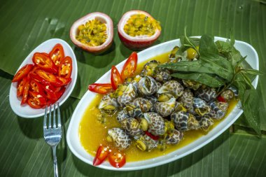 Steamed Spotted Babylon Blanching (Fresh Sea Babylonia Areolata Shell Boiled) served with passion fruit sauce goodtasty decorated with spices side view