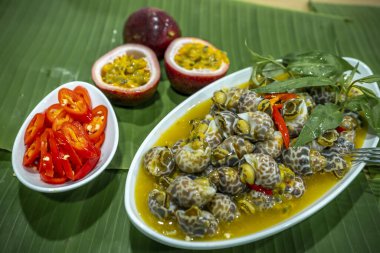 Steamed Spotted Babylon Blanching (Fresh Sea Babylonia Areolata Shell Boiled) served with passion fruit sauce goodtasty decorated with spices side view