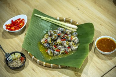 Steamed Spotted Babylon Blanching (Fresh Sea Babylonia Areolata Shell Boiled) served with passion fruit sauce goodtasty decorated with spices side view