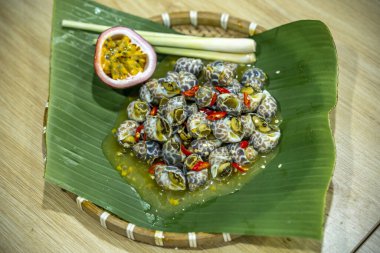 Steamed Spotted Babylon Blanching (Fresh Sea Babylonia Areolata Shell Boiled) served with passion fruit sauce goodtasty decorated with spices side view