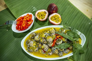 Steamed Spotted Babylon Blanching (Fresh Sea Babylonia Areolata Shell Boiled) served with passion fruit sauce goodtasty decorated with spices side view