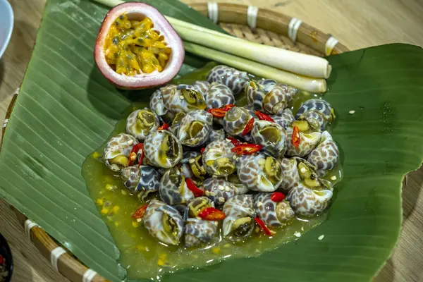 Steamed Spotted Babylon Blanching (Fresh Sea Babylonia Areolata Shell Boiled) served with passion fruit sauce goodtasty decorated with spices side view