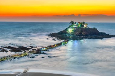 Hon Ba Adası, Vung Tau, Vietnam 'da küçük bir pagoda ile gün doğumu manzarası. İnsanlar ay ortasında tapınağı ziyaret etmek için kayalarda yürüyorlar. Geçmiş ve seyahat kavramı