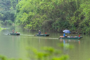 Ninh Binh, Vietnam - 5 Nisan 2024: Turistler Tam Coc Ulusal Parkı turu için tam Coc Nehri üzerinde mağaralara tekne ile yüzerler. Trang An, Ninh Binh, Vietnam.