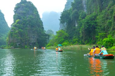 Ninh Binh, Vietnam - 5 Nisan 2024: Turistler Tam Coc Ulusal Parkı turu için tam Coc Nehri üzerinde mağaralara tekne ile yüzerler. Trang An, Ninh Binh, Vietnam.