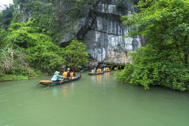 Ninh Binh, Vietnam - 5 Nisan 2024: Turistler Tam Coc Ulusal Parkı turu için tam Coc Nehri üzerinde mağaralara tekne ile yüzerler. Trang An, Ninh Binh, Vietnam.