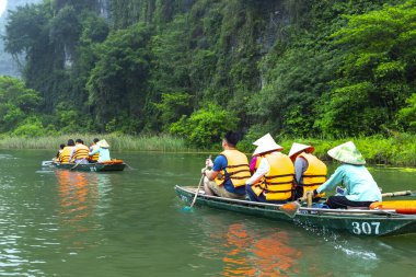 Ninh Binh, Vietnam - 5 Nisan 2024: Turistler Tam Coc Ulusal Parkı turu için tam Coc Nehri üzerinde mağaralara tekne ile yüzerler. Trang An, Ninh Binh, Vietnam.