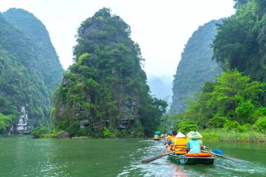 Ninh Binh, Vietnam - 5 Nisan 2024: Turistler Tam Coc Ulusal Parkı turu için tam Coc Nehri üzerinde mağaralara tekne ile yüzerler. Trang An, Ninh Binh, Vietnam.