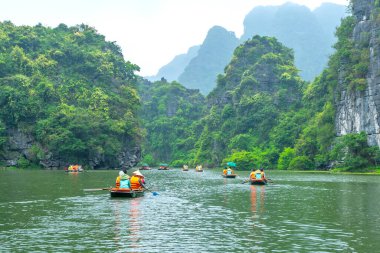 Ninh Binh, Vietnam - 5 Nisan 2024: Turistler Tam Coc Ulusal Parkı turu için tam Coc Nehri üzerinde mağaralara tekne ile yüzerler. Trang An, Ninh Binh, Vietnam.