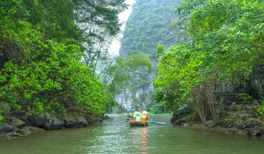Ninh Binh, Vietnam - 5 Nisan 2024: Turistler Tam Coc Ulusal Parkı turu için tam Coc Nehri üzerinde mağaralara tekne ile yüzerler. Trang An, Ninh Binh, Vietnam.