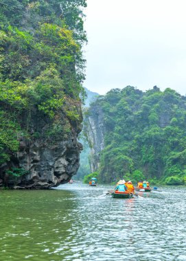 Ninh Binh, Vietnam - 5 Nisan 2024: Turistler Tam Coc Ulusal Parkı turu için tam Coc Nehri üzerinde mağaralara tekne ile yüzerler. Trang An, Ninh Binh, Vietnam.