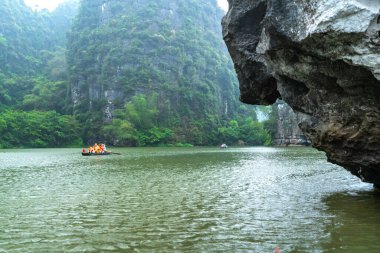 Ninh Binh, Vietnam - 5 Nisan 2024: Turistler Tam Coc Ulusal Parkı turu için tam Coc Nehri üzerinde mağaralara tekne ile yüzerler. Trang An, Ninh Binh, Vietnam.