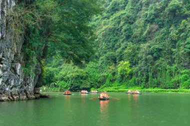 Ninh Binh, Vietnam - 5 Nisan 2024: Turistler Tam Coc Ulusal Parkı turu için tam Coc Nehri üzerinde mağaralara tekne ile yüzerler. Trang An, Ninh Binh, Vietnam.