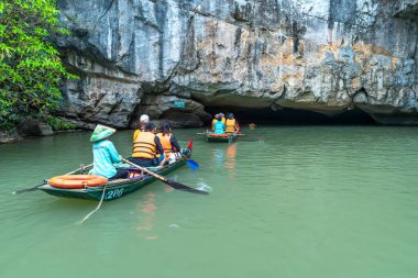 Ninh Binh, Vietnam - 5 Nisan 2024: Turistler Tam Coc Ulusal Parkı turu için tam Coc Nehri üzerinde mağaralara tekne ile yüzerler. Trang An, Ninh Binh, Vietnam.