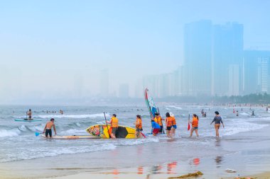 Da Nang, Vietnam - 15 Nisan 2024: Yüzücülerle ve uzaktaki modern otellerle dolu plaj.