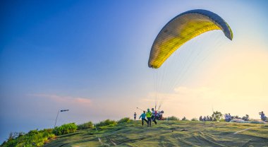 Da Nang, Vietnam - April 15th, 2024: Paragliding tour starts from the top of Son Tra mountain and lands at Da Nang beach for tourists who want to explore thrills in Da Nang, Vietnam clipart