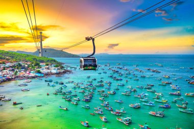 Dünyanın en uzun teleferik yolculuğu Güney Vietnam 'daki Phu Quoc adası, günbatımı gökyüzü. Aşağıda, popüler Hon Thom adasındaki An Thoi kasabasının limanında sıralanmış geleneksel balıkçı tekneleri var..