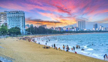 Quy Nhon, Vietnam - 17 Nisan 2024 Quy Nhon plajı öğleden sonra yürüyen ve yüzen insanlarla doludur..