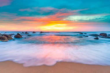 Sahilde gün batımı kayalar ve dalgalarla.