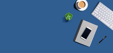 Masa ögeleri - klavye, akıllı telefon, kahve ve yukarıdan bir kalem.