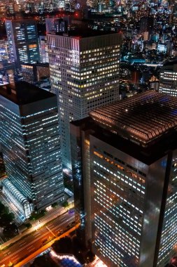 Nishi-Shinjuku, Tokyo, Japonya 'nın gece şehir manzarasının üzerinde gökdelenler yükseliyor.